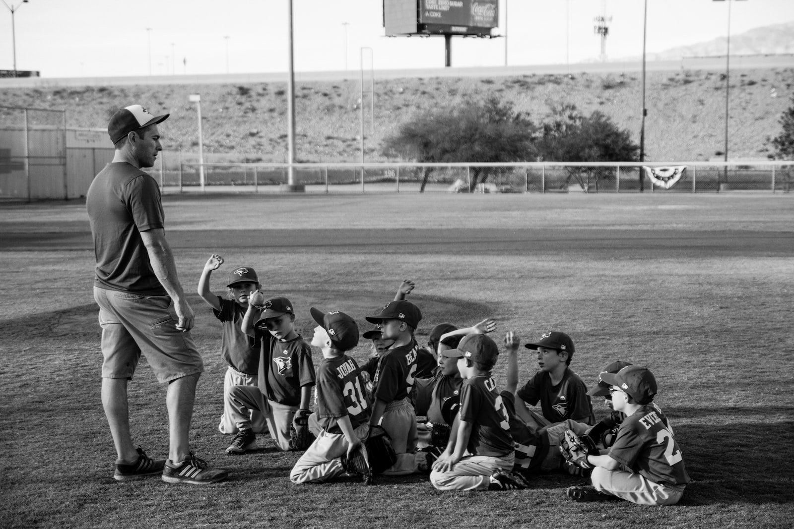 grayscale photo of boys football team in front of coach